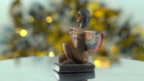 Dreamy-close-up-shot-of-a-Cleopatra-statue-with-wide-open-bird-wings,-shiny-golden-depth-of-field,-Egyptian-historical-ruler,-antique-artwork-of-a-goddess,-rotating-360-cinematic-static-4K-video