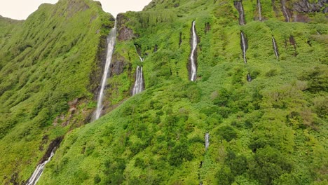 Flying-towards-row-of-waterfalls-Poço-Ribeira-do-Ferreiro-at-Flores-island,-aerial