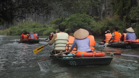 Row-boats-Ninh-Binh-Vietnam,-tourists-rowing-in-slomotion