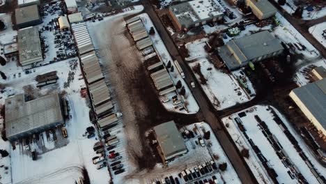 Aerial-shot-of-a-lone-semi-truck-driving-in-an-industrial-area-among-warehouses