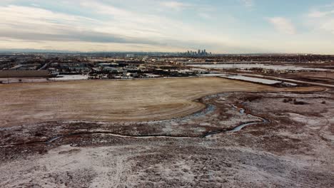 Winter-landscape-over-frozen-fields-in-Alberta,-Canada,-with-the-Calgary-downtown-in-the-far-background