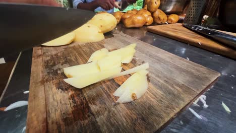 Hände-Mit-Einem-Messer-Schneiden-Die-Kartoffeln-Auf-Dem-Holzbrett-In-Der-Küche