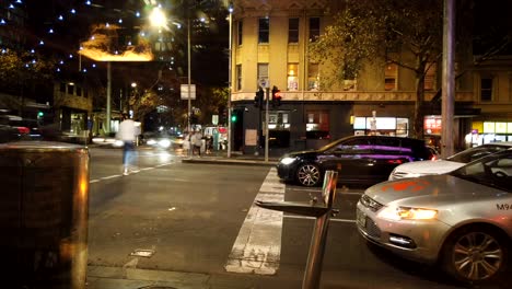Melbourne-intersection,-motion-lapse-of-cars-people-walking-and-reflections-from-restaurant