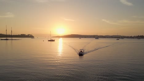 Small-motorboat-navigate-in-harbour-bay-in-Porto-Heli,-Greece-at-sunset