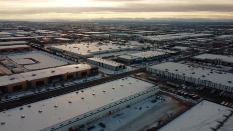 Beautiful-winter-aerial-shot-of-giant-warehouses-with-the-Rocky-Mountains-in-the-background-in-Calgary