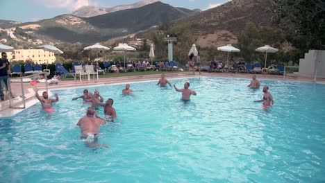 Wasserball-Im-Pool-Im-Urlaub-Unter-Freunden-Mit-Bergigem-Hintergrund-Auf-Kreta,-Griechenland,-Zeitlupe
