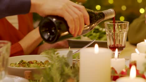 Close-up-shot-of-the-man-pouring-the-red-wine-in-the-glass-during-the-winter-holiday-celebration