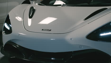 Front-bumper-of-white-McLaren-720S-with-studio-lighting-reflecting,-luxury-sportscar