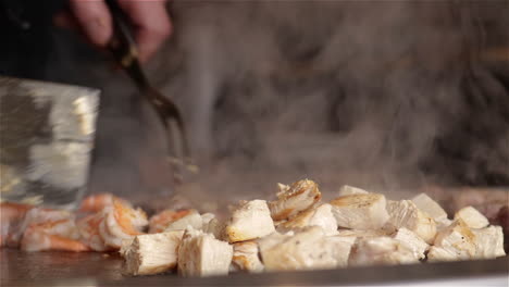 Japanischer-Koch-Schneidet-Und-Kocht-Fleisch,-Während-Es-Auf-Einem-Teppanyaki-Flachgrill-Kocht