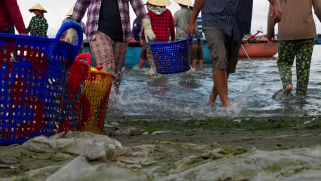 Closeup-shot-of-hectic-fishermen-taking-baskets-of-fish-to-shore-from-basket-boat,-Mui-Ne-fishing-Village,-vietnam