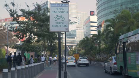 Smart-roads-in-smart-city-with-emission-signage-board,-smooth-city-road-traffic-flow,-new-India-financial-and-residential-complex-Bandra-Kurla-Complex-skyline-buildings-in-view