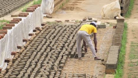 Laborer-moves-raw-bricks-from-drying-area-over-to-stack-and-organize