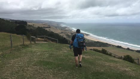 The-young-man-on-backpacking-road-trip-adventure-admiring-the-view-on-a-hike-along-the-great-ocean-road,-victoria-Australia