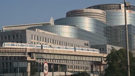 Modern-India-business-center-skyline-office-buildings-of-IndusInd-bank-and-other-companies-at-DLF-cyber-city-with-the-iconic-view-of-rapid-metro-crossing-through-flyover,-Gurugram