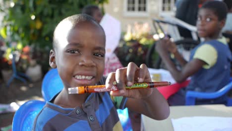 Niños-Africanos-Con-Discapacidades-Participan-Felizmente-En-Actividades-De-Pintura-Al-Aire-Libre-En-Un-Día-Soleado,-Mostrando-Su-Creatividad-Y-Alegría.