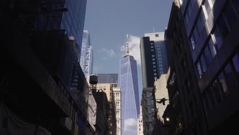 Pov-walk-in-street-of-New-York-with-view-on-mirrored-One-World-Trade-Center-during-sunny-day-in-NYC
