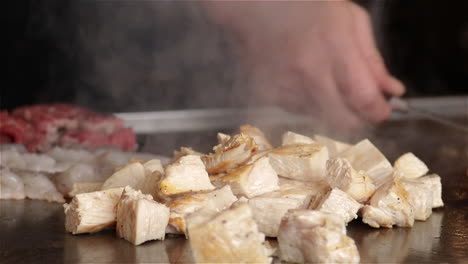 Der-Japanische-Koch-Schneidet-Und-Kocht-Garnelen,-Rindfleisch-Und-Hühnchen-Auf-Einem-Teppanyaki-Flachgrill