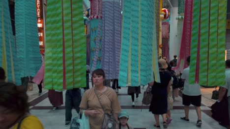 People-in-arcade-walking-through-decorative-paper-streamers-during-Tanabata-festival