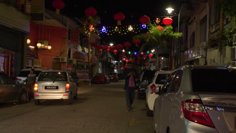 Person-Walking-Down-Busy-Street-at-Night,-Little-India,-Lantern-Lights,-Malaysia