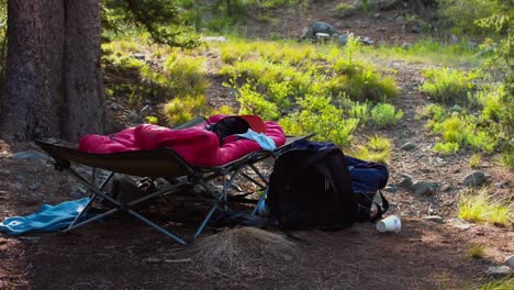 Folding-bed-cot,-sleeping-bag,-camping-gear-on-the-ground-at-camp-site