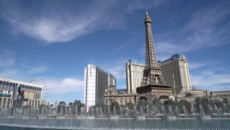 Die-Springbrunnen-Von-Bellagio-Zeigen-Sich-An-Einem-Sonnigen-Tag-In-Las-Vegas-Mit-Dem-Eiffelturm-Im-Hintergrund-Und-Blauem-Himmel