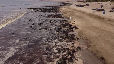 Oil-worker-walks-on-contaminated-beach