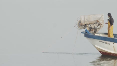 Kleines-Fischerboot-Sammelt-Fischernetze,-Während-Ein-Arbeiter-In-Ruhiger-See-Bei-Sonnenaufgang-In-Zeitlupe-60-Fps-Eine-Zigarette-Raucht