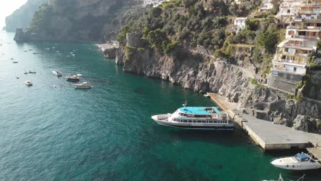 Positano,-Amalfi-Coast---aerial-descending-shot-on-the-small-port-and-the-coastline-on-a-sunny-day