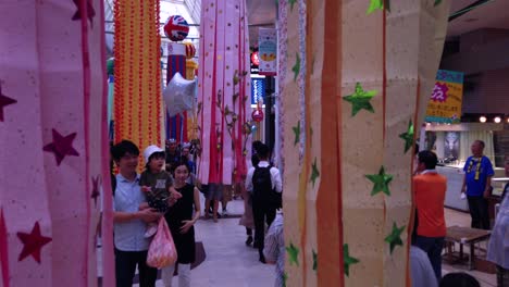 People-on-busy-street-walking-through-decorative-paper-streamers-during-Tanabata-festival-in-slow-motion