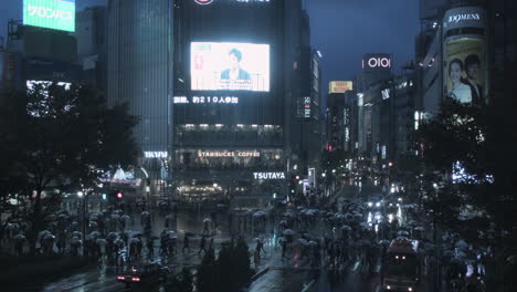 Busy-Tokyo-Cityscape-with-the-Roads-Crowded-with-Pedestrians-Using-Umbrellas-at-Night-Time