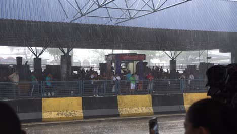 Manaus,-Brazil,-Heavy-Rainfall-on-Road-and-Bus-Station,-People-Hiding-Under-Roof