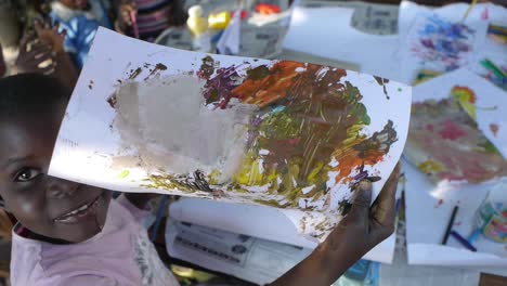 Un-Niño-Muestra-Obras-De-Arte-Pintadas-Con-Los-Dedos-En-Mongu,-Zambia