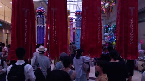 Menschen-Auf-Einer-Belebten-Straße,-Die-Während-Des-Tanabata-Festivals-In-Zeitlupe-Durch-Dekorative-Papierschlangen-Laufen