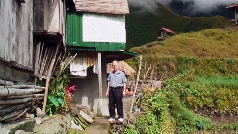 Man-talking-outside-a-shanty-on-top-of-a-hill-near-a-cliff-in-Bataad,-Philippines-in-springtime