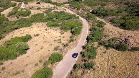 Drone-Aerial-shot-following-a-car-driving-on-a-narrow-countryside-road-towards-the-coast