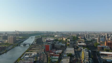 Drone-shot-following-Harlem-river,-over-the-cityscape-of-Bronx,-golden-hour-in-New-York,-USA