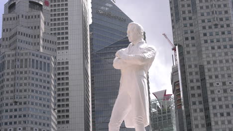 Estatua-De-Sir-Thomas-Stamford-Raffles-De-Pie-Con-Los-Edificios-Del-Distrito-Central-De-Negocios-De-La-Ciudad-Al-Fondo-Junto-Al-Río-Singapur.