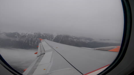 View-out-window-as-aeroplane-takes-off-over-snowy-mountains,-Innsbruck,-Austria