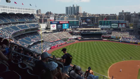 New-York-Yankees-stadium-on-a-sunny-day,-moderately-crowded,-panning-right-to-left-with-people-walking-up-the-steps
