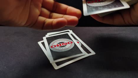 Close-up-shot-of-male-hands-laying-out-playing-cards-from-the-deck-one-by-one-on-a-black-table