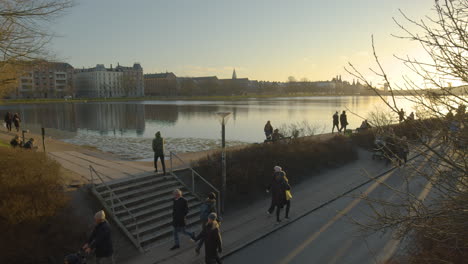 Beautiful-view-of-people-walking-past-river-side-at-sunset-in-Copenhagen,-Denmark