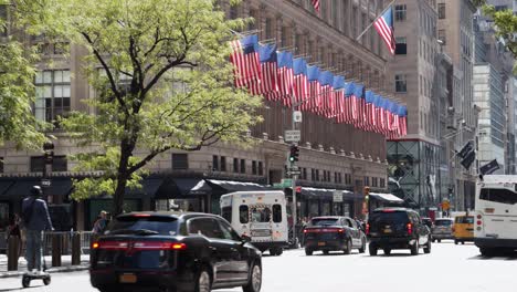 Viele-US-Flaggen-An-Einem-Gebäude,-Während-Auf-Der-Straße-Starker-Verkehr-Herrscht