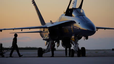 Maintenance-team-member-walks-in-front-of-silhouetted-Blue-Angels-prep-during-early-morning-sunrise-in-slow-motion