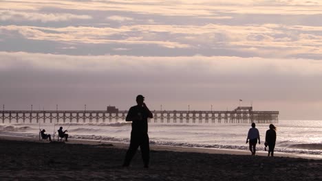People-walking-about-in-early-morning-near-Apache-Pier-at-Myrtle-Beach,-South-Carolina
