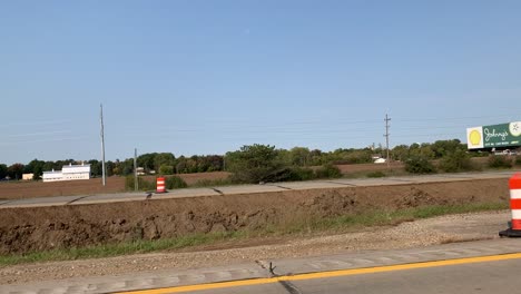 Conduciendo-Por-Una-Autopista-De-Michigan-Durante-La-Construcción-De-Carreteras-Con-Maquinaria-Pesada,-Camiones-Volquete-Y-Excavadoras