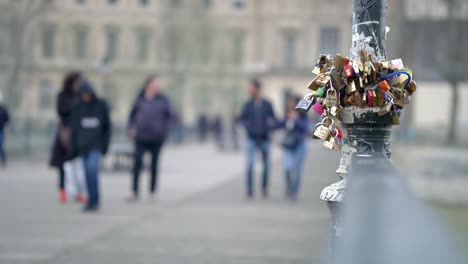 Slow-motion-clip-of-love-locks-on-a-pole-in-paris-city-centre-with-people-walking-out-of-focus-blur-in-the-background