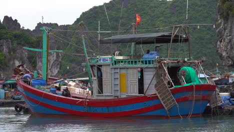 Traditionelles-Vietnamesisches-Fischerboot-Mit-Besatzung,-Das-Zwischen-Kalksteininseln-Der-Halong-Bucht-Steht