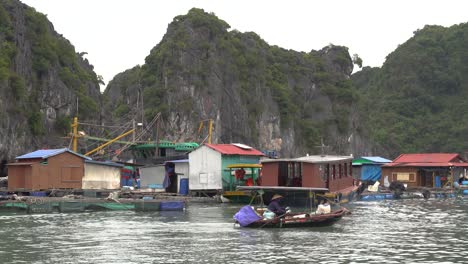 Vietnamesin-Rudert-Mit-Einem-Kleinen-Boot-Durch-Ein-Schwimmendes-Dorf-In-Der-Halong-Bucht
