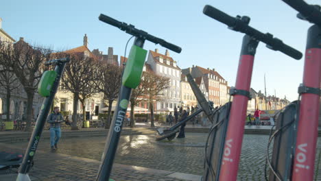 Lime-and-Voli-Electric-Scooters,-parked-stationary-in-famous-Nyhavn-district-of-Copenhagen,-Denmark