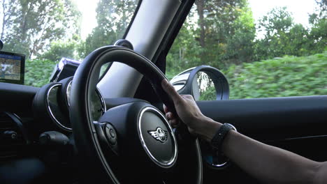 Close-up-shot-on-the-steering-wheel-of-a-mini-cooper-driven-on-the-road